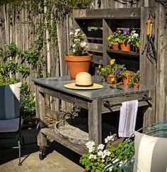 an old wooden table with potted plants on it and a hat sitting on top