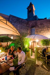 people are sitting at tables outside in the evening