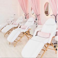 a row of white chairs sitting in front of a pink wall with curtains on it