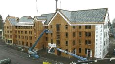 a house being built with wooden siding and windows on the front, surrounded by construction equipment