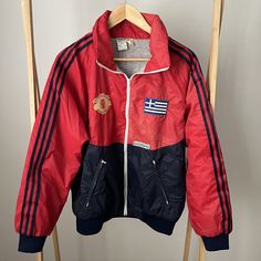 This vintage Adidas Manchester United wind breaker is a rare and highly collectable item.  For all the football fans this jacket is in fabulous condition with the Manchester United Football Club emblem on the front.  There are two badges on the other side - an Adidas one and another one - the Greek flag - looks like its been added by the owner and hand stitched on.  If you hate this it look easy to take off as its been just hand stitched.   All zips work perfectly.  There are no stain or holes i Red Throwback Outerwear For Sports Events, Vintage Winter Track Jacket For Sports Events, Vintage Long Sleeve Track Jacket For Sports, Retro Red Sports Windbreaker, Retro Red Windbreaker For Sports, Retro Red Track Jacket For Outdoor, Red Retro Track Jacket For Outdoor, Vintage Red Track Jacket For Outdoor, Vintage Red Sports Outerwear