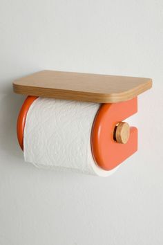 an orange and white toilet paper holder with a wooden shelf on the wall behind it