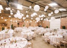 tables and chairs are set up for an event with paper lanterns hanging from the ceiling