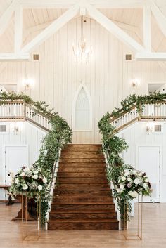 the wedding ceremony was decorated with greenery and white flowers, along with wooden stairs