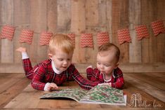 two young boys are laying on the floor and looking at an open book while wearing matching pajamas