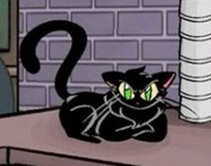 a black cat sitting on top of a wooden table next to a brick wall with green eyes