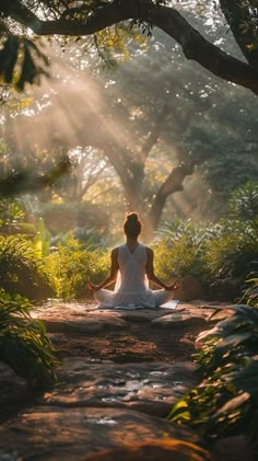 a woman is sitting in the middle of a forest and meditates with her eyes closed