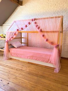 a pink canopy bed with flowers on the top and bottom, in a loft bedroom