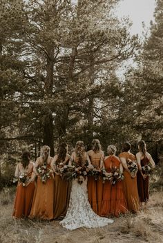 a group of women standing next to each other in front of some trees and grass