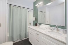 a white bathroom with blue walls and tile flooring, along with a shower curtain