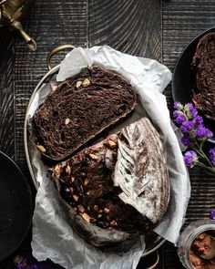 a loaf of bread sitting on top of a wooden table next to some purple flowers