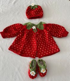 a red knitted doll outfit with matching shoes and booties on a white surface