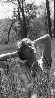 a black and white photo of a woman laying in tall grass