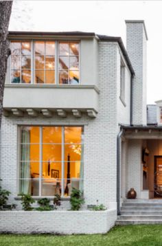 a white brick house with large windows and steps leading up to the front door area