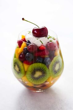 a fruit salad in a wine glass with cherries and kiwis