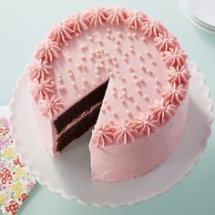 a pink cake with chocolate frosting and sprinkles sits on a plate