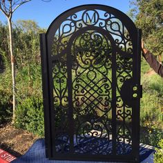 a man is holding up an ornate iron gate in the middle of a park area