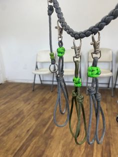 there are several ropes hanging from the ceiling in this room with chairs behind them and one has green cords attached to it