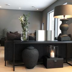 a living room filled with furniture and a vase on top of a table next to a lamp