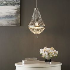 a chandelier hanging over a table with flowers on it