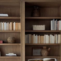 an open bookcase with books and vases on the shelves in front of it