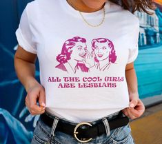 The "All Cool Girls Are Lesbians" t-shirt is the perfect addition to any LGBTQ+ wardrobe. This unisex graphic tee features a bold and eye-catching design that proudly displays a message of inclusivity and acceptance. Crafted from high-quality materials, this t-shirt is designed for long-lasting wear and maximum comfort Pride Apparel, Pride Event, Active Wear Dresses, Lesbian Shirts, Pansexual Pride, White Graphic Tee, Pride Outfit, Club Shirts, Lgbt Pride