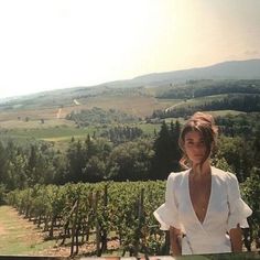 a woman standing in front of a lush green hillside