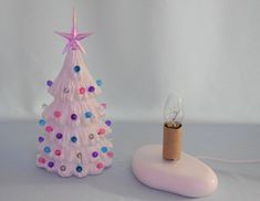 a small white christmas tree next to a tiny light on a stand with a corkscrew