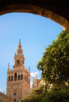 a tall tower with a clock on it's side next to trees and bushes