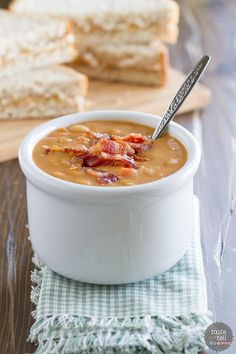 a white bowl filled with soup next to two pieces of bread on a cutting board