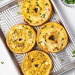 four mini quiche pies sitting on top of a metal baking tray next to some parsley