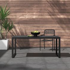 a black table with two chairs and a bowl of fruit on it next to a wooden wall