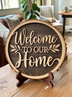 a wooden sign that says welcome to our home on top of a table in front of a couch