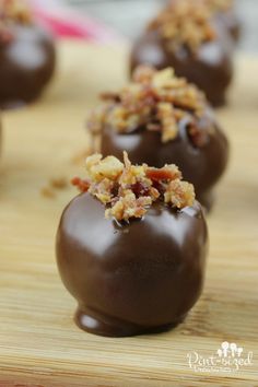 chocolate covered candies are sitting on a cutting board with chopped walnuts in the middle