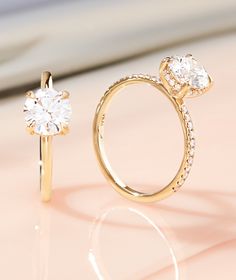 two gold rings with diamonds on them sitting next to each other