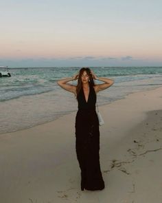 a woman in a black dress standing on the beach