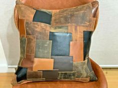 a brown leather chair with a patchwork pillow on it's back and side