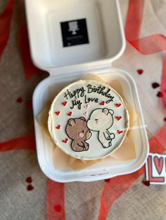 a birthday cake with an elephant and bear on it in a white plastic container next to red streamers