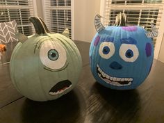 two pumpkins decorated to look like monsters sitting on a table