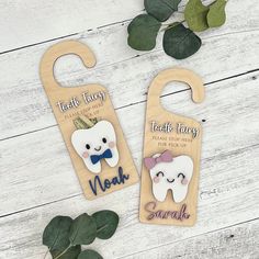 two wooden teeth with bow ties are on display next to some leaves and greenery