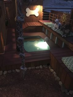 a hot tub in the middle of a wooden deck with lights on and a dog statue next to it