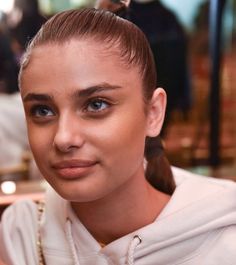 a close up of a person with a necklace on her neck and hair in a ponytail