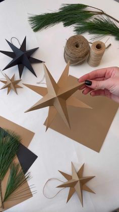 someone is making christmas decorations out of brown paper and twine on a white table