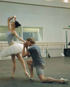 a man kneeling down next to a ballerina