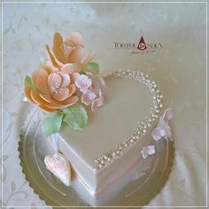 a heart shaped cake with flowers and pearls