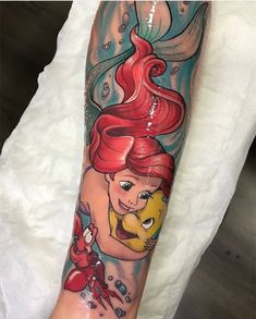 the little mermaid tattoo is on someone's arm