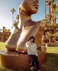 a woman is standing in front of a large statue with her hands on her hips