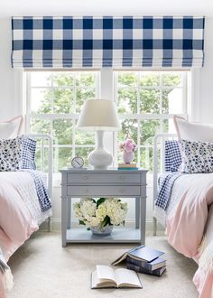 two twin beds with blue and white bedding in front of a window next to each other