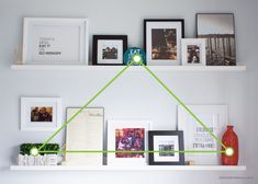 a white shelf with pictures on it and green lines going across the shelves above them