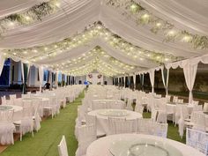 tables and chairs are set up under white draping with fairy lights hanging from the ceiling